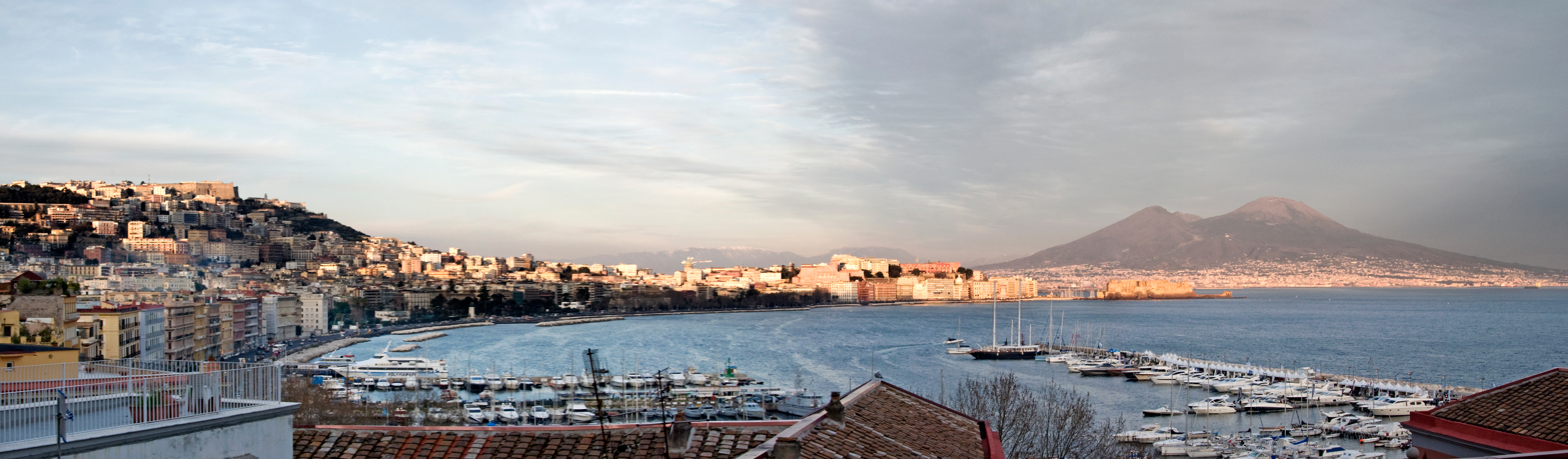 Il golfo di Napoli al tramonto, con il Vesuvio innevato e il porto